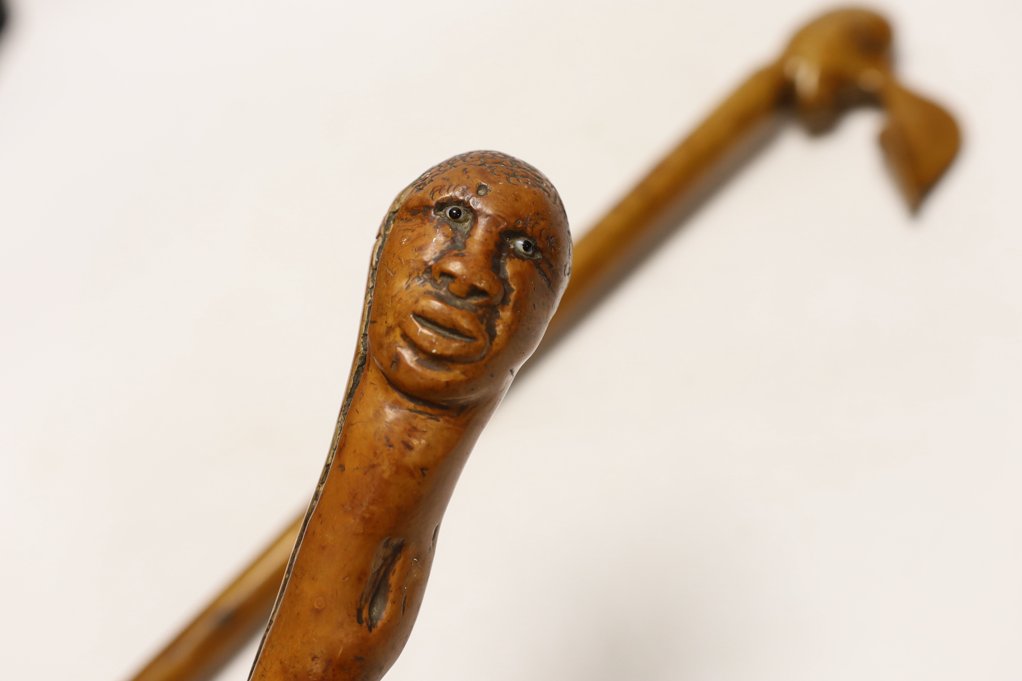 Two walking canes including a Greek olive wood example with carved head handle, largest 89cm in length